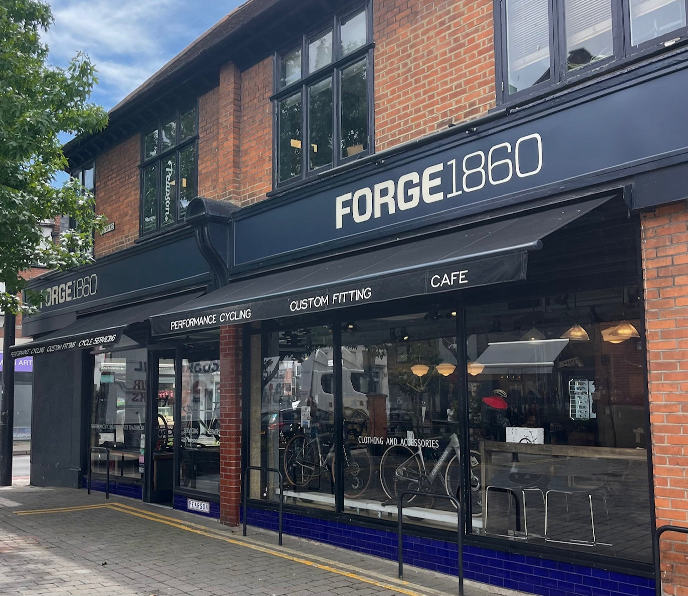 Storefront of Forge 1860 bike shop with glass windows and blue awning.